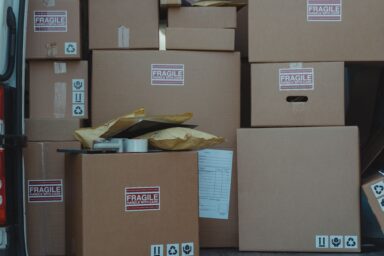 Stacked cardboard boxes with fragile and recycling labels next to a delivery van