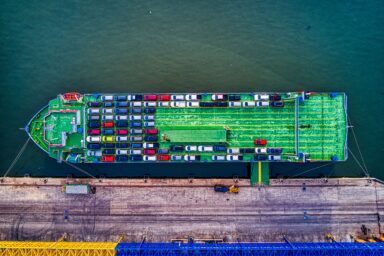 Aerial view of a car carrier ship loaded with rows of cars, moored at a port quay