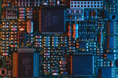 Close-up of a circuit board with microchips and electronic components lit in blue and orange